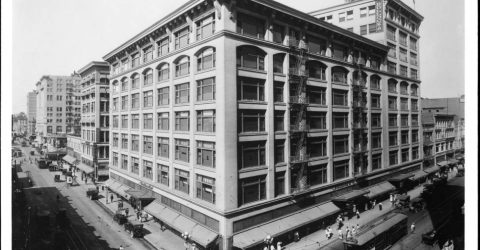 Photograph of a view of the corner of Seventh and Broadway looking west, showing Bullock's Department Store, Los Angeles, ca.1920. The seven-story department store stands at center, 7th Street and Broadway extending out to either side of it.
