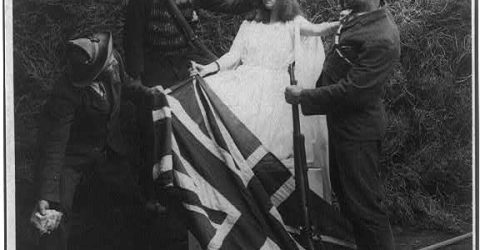 Three men dressed as Boers trampling Union Jack and preparing to assail woman dressed as Brittania.