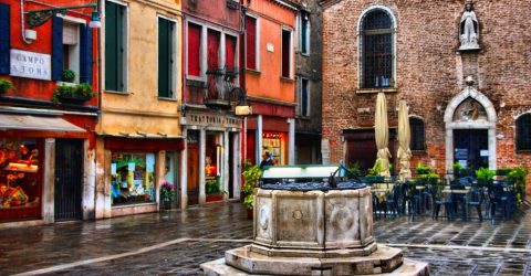 An Italian plaza glistens colorfully in the rain.